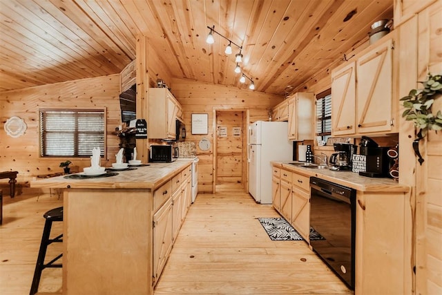 kitchen featuring black appliances, light hardwood / wood-style flooring, vaulted ceiling, tile counters, and a breakfast bar area