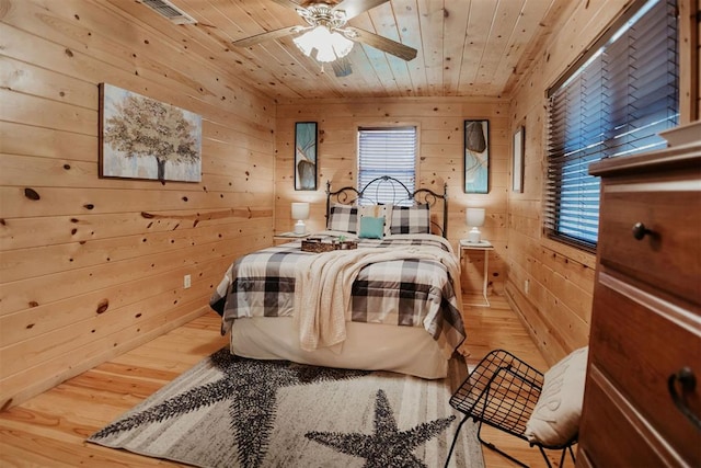 bedroom with wooden walls, hardwood / wood-style floors, ceiling fan, and wooden ceiling