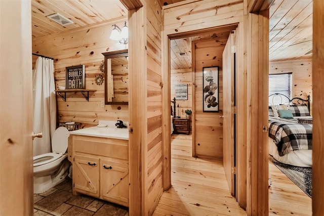 bathroom featuring wooden ceiling, wood walls, hardwood / wood-style floors, toilet, and vanity