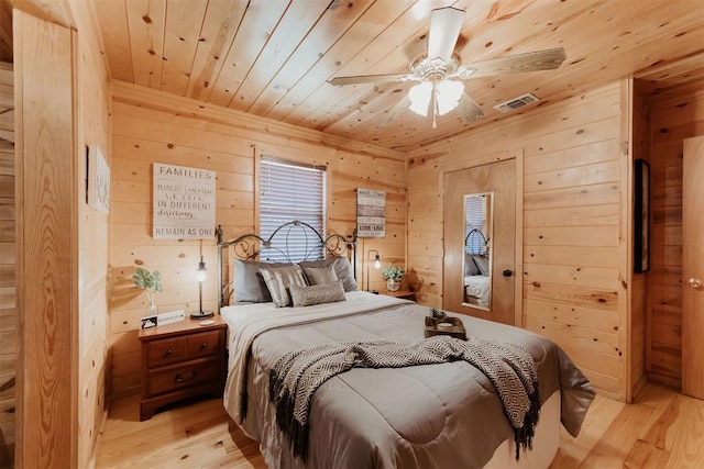 bedroom with ceiling fan, wood ceiling, wooden walls, and light hardwood / wood-style flooring