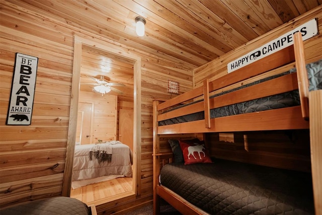 bedroom with ceiling fan, wood walls, and wood ceiling