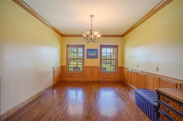 unfurnished room featuring a notable chandelier, dark hardwood / wood-style flooring, and ornamental molding