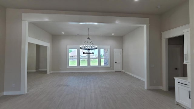 unfurnished dining area featuring a notable chandelier and light hardwood / wood-style flooring