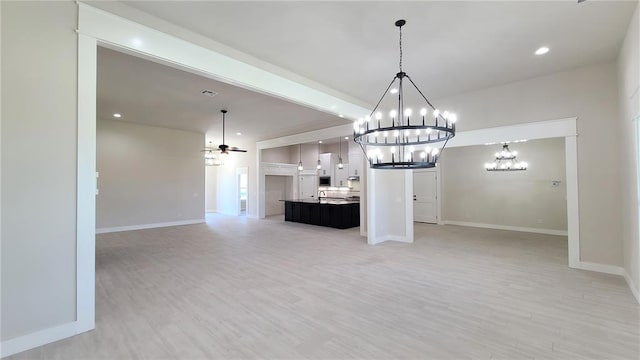 unfurnished living room with light hardwood / wood-style floors and ceiling fan with notable chandelier