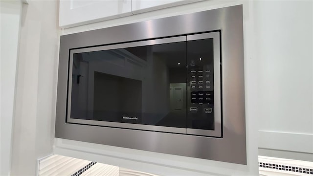 interior details featuring white cabinets and stainless steel microwave