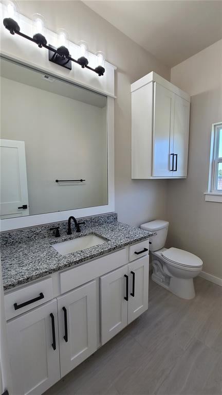 bathroom with vanity, toilet, and wood-type flooring