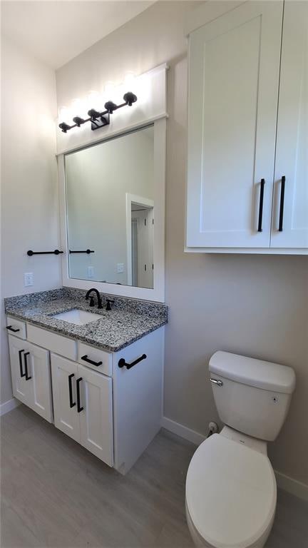 bathroom with hardwood / wood-style floors, vanity, and toilet