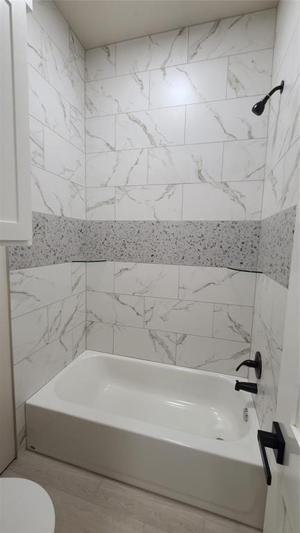 bathroom featuring toilet and tiled shower / bath