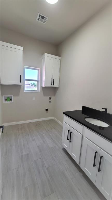 washroom featuring cabinets, sink, hookup for a washing machine, light wood-type flooring, and hookup for an electric dryer