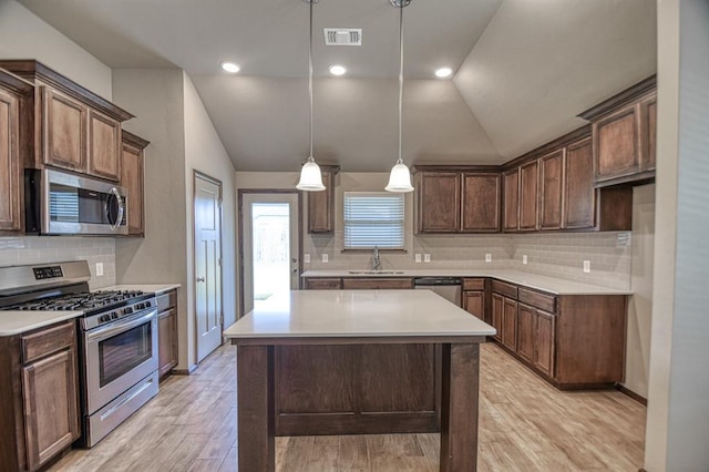 kitchen featuring lofted ceiling, sink, appliances with stainless steel finishes, decorative light fixtures, and light hardwood / wood-style floors