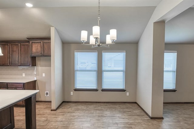 kitchen with pendant lighting, decorative backsplash, dark brown cabinetry, and a chandelier