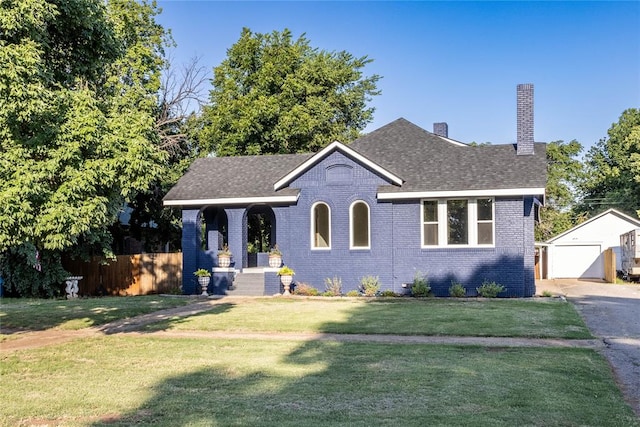 view of front of house with covered porch, a garage, an outdoor structure, and a front yard