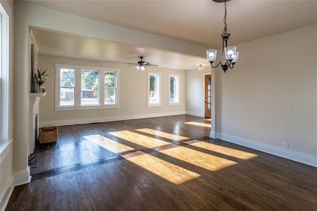 unfurnished living room with ceiling fan with notable chandelier and dark wood-type flooring