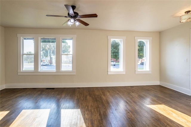 spare room with dark hardwood / wood-style floors, ceiling fan, and a wealth of natural light