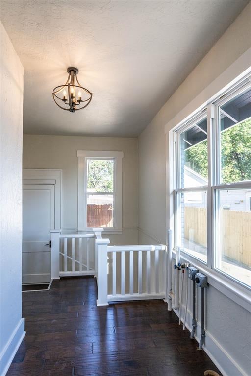 additional living space with dark hardwood / wood-style flooring and an inviting chandelier