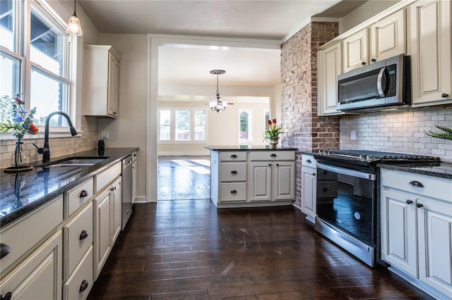 kitchen with dark wood-type flooring, sink, hanging light fixtures, and appliances with stainless steel finishes