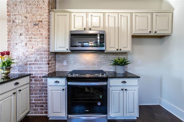 kitchen with white cabinetry, stainless steel appliances, dark hardwood / wood-style flooring, dark stone countertops, and decorative backsplash