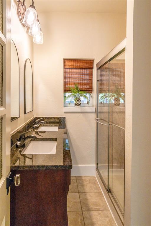 512 N College St, Cordell, OK 73632 - bathroom with double vanity, a stall shower, tile patterned flooring, and baseboards