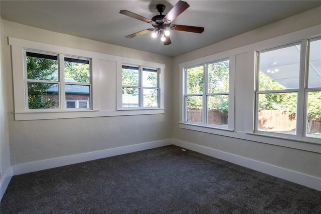 empty room with ceiling fan and dark colored carpet