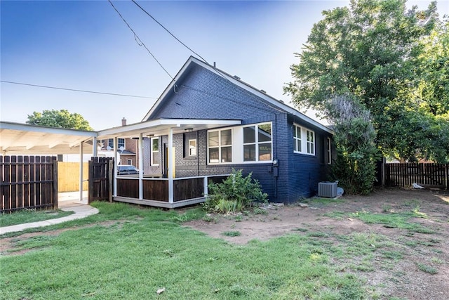 rear view of property with central AC unit and a yard