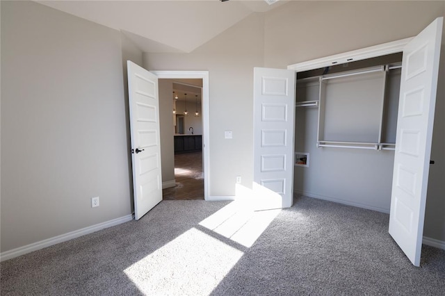 unfurnished bedroom with carpet floors, a closet, vaulted ceiling, and sink