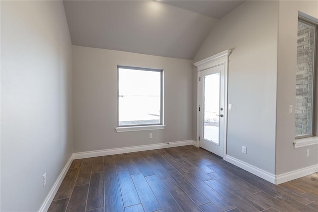 spare room featuring vaulted ceiling, dark hardwood / wood-style flooring, and a wealth of natural light