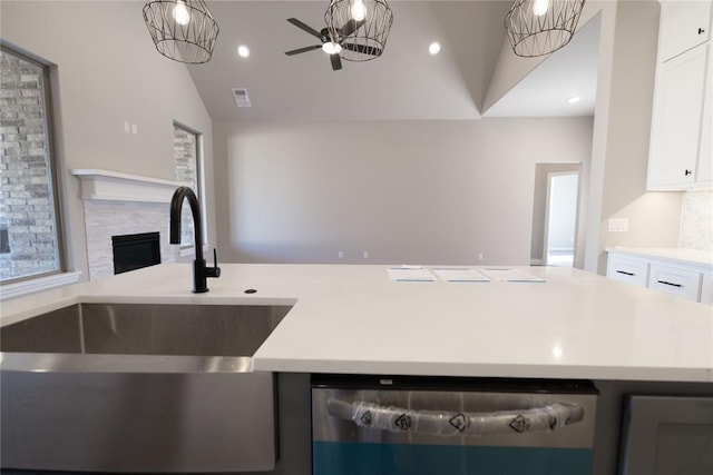 kitchen featuring white cabinetry, lofted ceiling, a fireplace, and sink