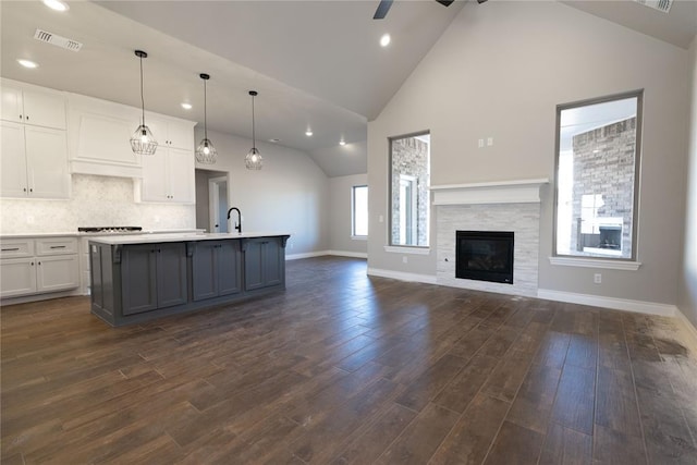 kitchen featuring decorative light fixtures, white cabinetry, dark hardwood / wood-style floors, and a center island with sink