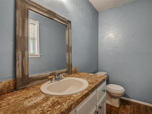 bathroom with toilet, vanity, and hardwood / wood-style flooring