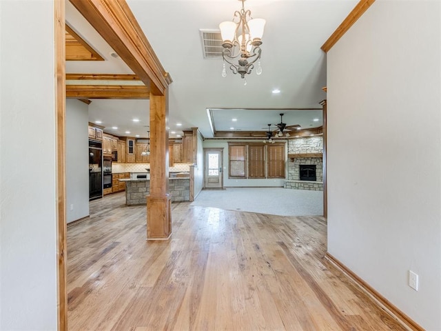 unfurnished living room with a fireplace, crown molding, light hardwood / wood-style flooring, and ceiling fan with notable chandelier