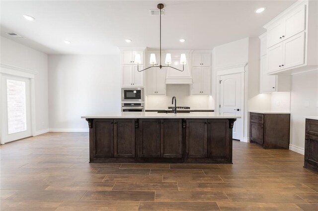 kitchen featuring white cabinetry, light countertops, built in microwave, and oven