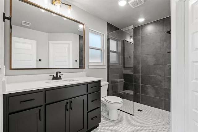 bathroom featuring tile patterned flooring, a tile shower, vanity, and toilet