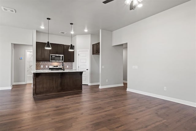 kitchen with backsplash, dark wood-type flooring, hanging light fixtures, ceiling fan, and appliances with stainless steel finishes