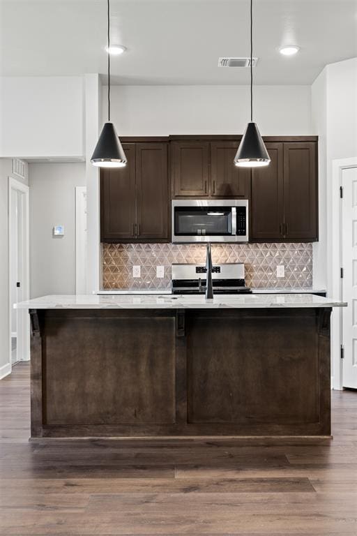 kitchen with dark brown cabinetry, hanging light fixtures, stainless steel appliances, and dark hardwood / wood-style flooring