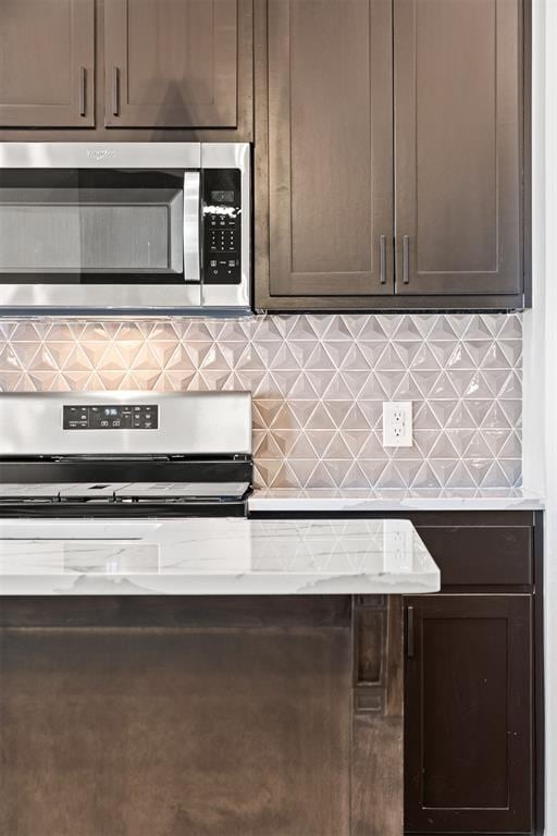 kitchen featuring dark brown cabinetry, decorative backsplash, and stainless steel appliances