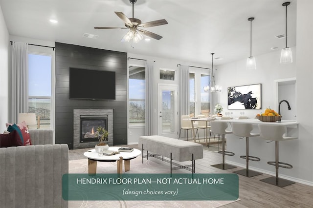 living room featuring ceiling fan, a large fireplace, and wood-type flooring