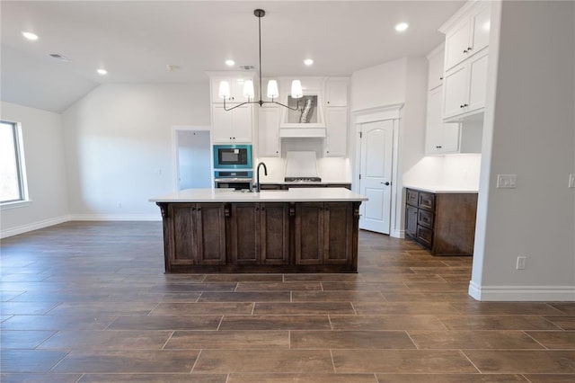 kitchen with dark brown cabinetry, stainless steel appliances, a kitchen island with sink, sink, and decorative light fixtures