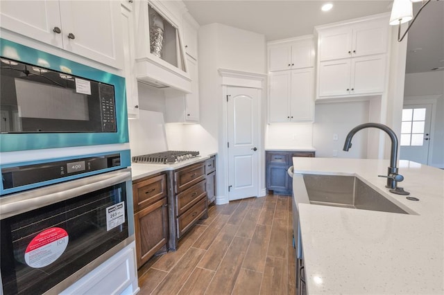 kitchen with light stone countertops, white cabinetry, sink, and stainless steel appliances