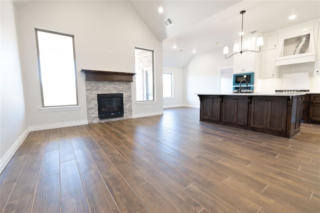 kitchen featuring dark brown cabinets, sink, pendant lighting, a fireplace, and a chandelier