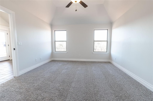 carpeted spare room with ceiling fan, a healthy amount of sunlight, and lofted ceiling