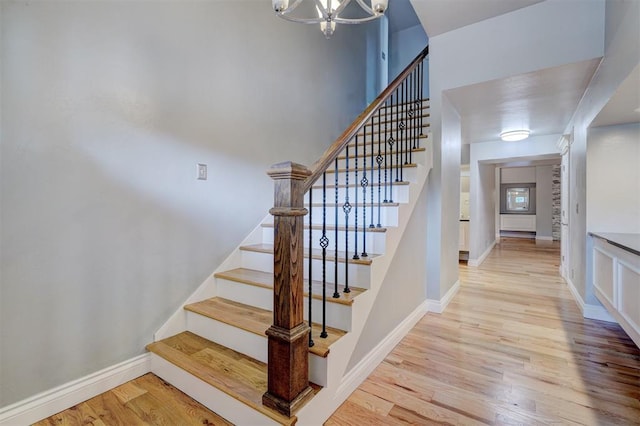 stairs with hardwood / wood-style flooring and an inviting chandelier