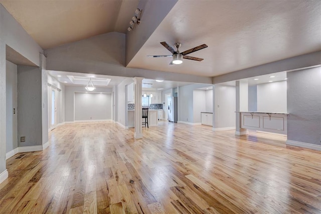 unfurnished living room with ceiling fan, light wood-type flooring, and lofted ceiling