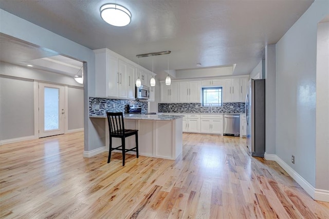 kitchen with white cabinetry, light wood-type flooring, kitchen peninsula, and appliances with stainless steel finishes