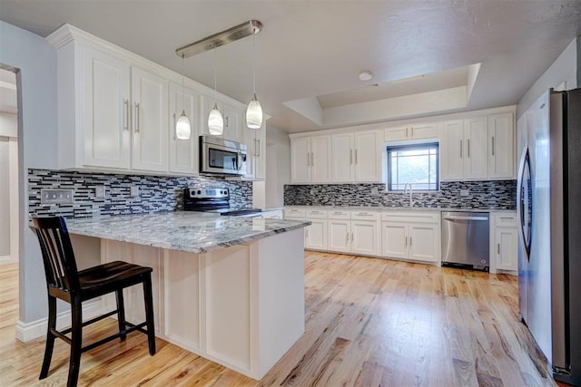 kitchen with white cabinetry, light wood-type flooring, kitchen peninsula, and appliances with stainless steel finishes