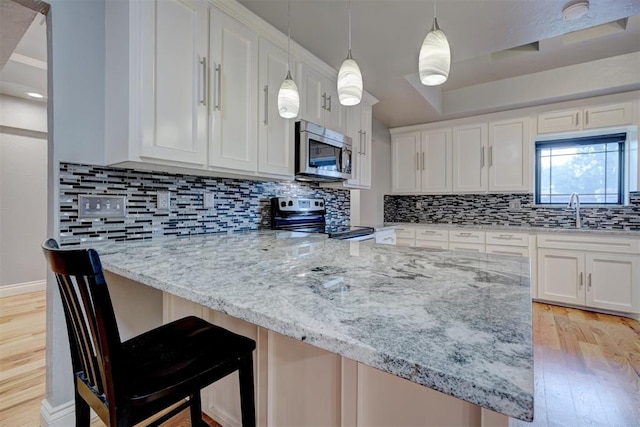 kitchen featuring white cabinets, sink, light wood-type flooring, tasteful backsplash, and stainless steel appliances