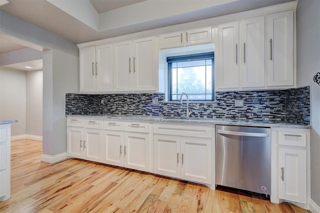 kitchen featuring light stone countertops, tasteful backsplash, stainless steel dishwasher, white cabinets, and light hardwood / wood-style floors