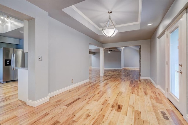 unfurnished dining area featuring a raised ceiling, ceiling fan, and light hardwood / wood-style floors