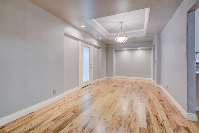 unfurnished room featuring light hardwood / wood-style flooring and a tray ceiling