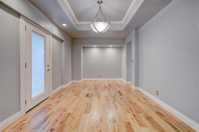 interior space with light hardwood / wood-style floors, a raised ceiling, and crown molding