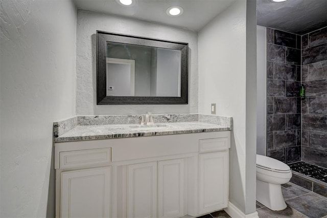 bathroom featuring tile patterned flooring, vanity, toilet, and a tile shower